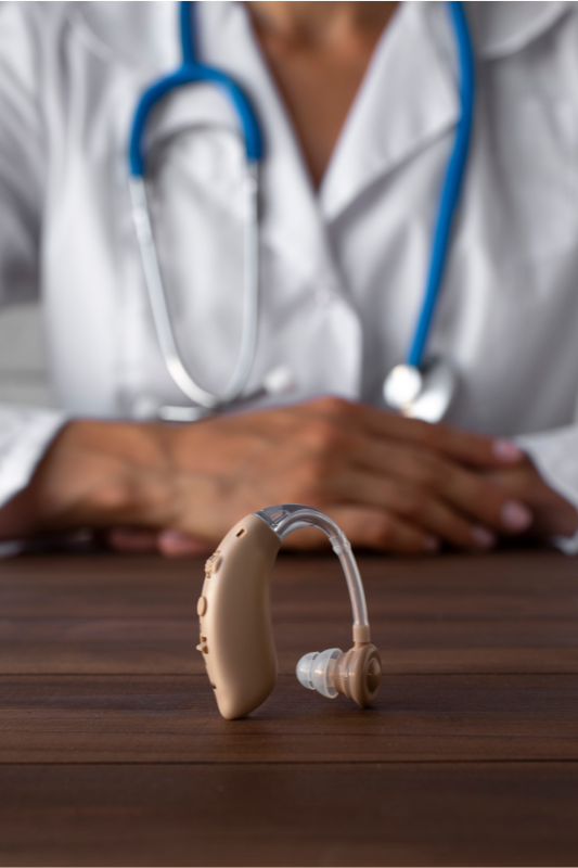 Doctor with hearing aid on table
